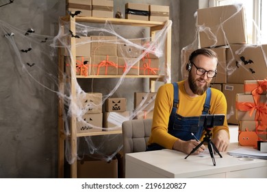 Startup Small Business Entrepreneur Or Freelance Caucasian Man On Halloween Taking Order Online Video Call Using Smart Phone. Online Marketing Packaging Box And Shipping. Copy Space.