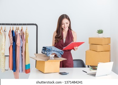 Startup small business entrepreneur SME, asian woman packing cloth in box. Portrait young Asian small business owner home office, online sell marketing delivery, SME e-commerce telemarketing concept  
