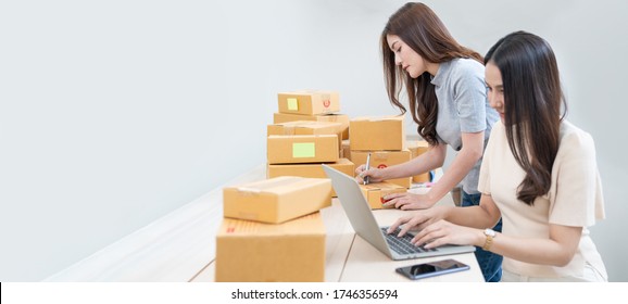 Startup small business owner working with computer at workplace. Freelance two woman seller check product order. Packing goods for delivery to customer. Online selling. E-commerce. Online Shopping
