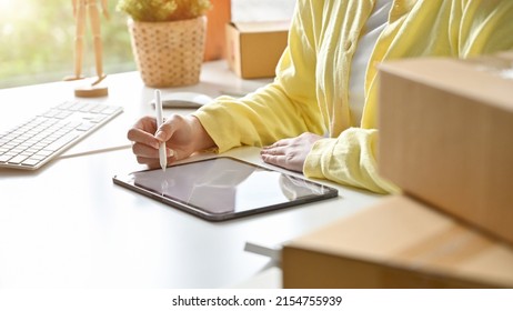 Startup Small SME Business Entrepreneur Female Sitting At The Desk, Using Digital Tablet To Create Her Online Marketing Content. Cropped Closeup Image