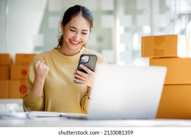 Startup SME small business entrepreneur SME of freelance Asian woman using a laptop with box Cheerful success Asian woman her hand lifts up online marketing packaging box and delivery SME idea concept