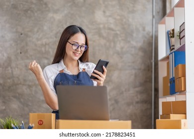 Startup SME small business entrepreneur of freelance Asian woman using a laptop with box Cheerful success happy Asian woman her hand lifts up online marketing packaging and delivery SME idea concept