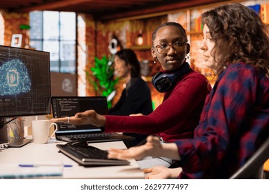 Startup software developers doing brainstorming to do rapid technological advancement in AI industry. African american woman and coworker leveraging machine learning tech to gain competitive edge
