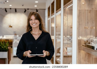 Startup successful small business owner sme beauty woman stand with tablet smartphone in jewelry store. - Powered by Shutterstock