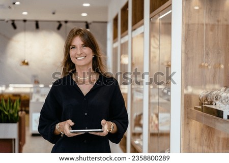 Startup successful small business owner sme beauty woman stand with tablet smartphone in jewelry store.