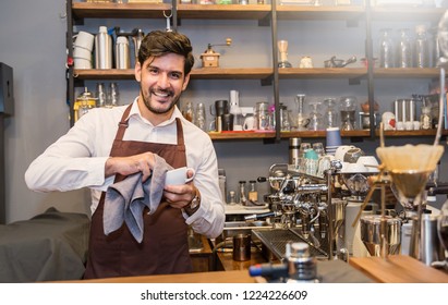 Startup successful sme small business entrepreneur owner man cleaning cup at counter bar coffee shop restaurant. Portrait of young caucasian seller man successful barista cafe owner job modern worker. - Powered by Shutterstock