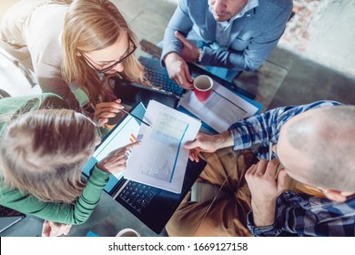 Startup Team Of Businesspeople Looking At Business Plan Financials, Top Down View