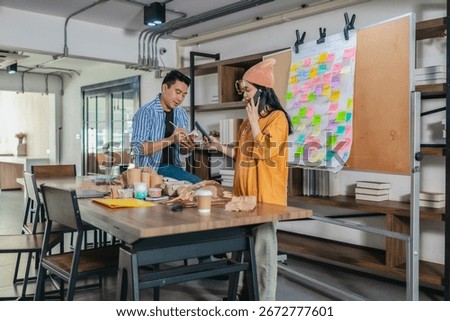 Startup team collaborates using Agile-style task board  to organize, plan, track the development of sustainable packaging products. Workspace is filled with prototypes and creative planning materials