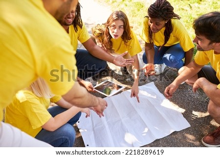 Start-up team with a map in the field game geocaching for advice and team building