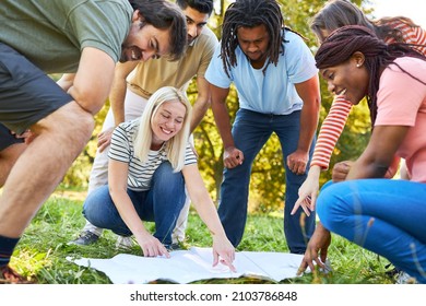 Start-up team people look at the map during the treasure hunt in the geocaching game - Shutterstock ID 2103786848