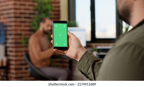 Startup Worker Using Isolated Greenscreen On Mobile Phone, Looking At Blank Mockup Display With Copyspace Background. Analyzing Chroma Key Template On Modern Smartphone Display.