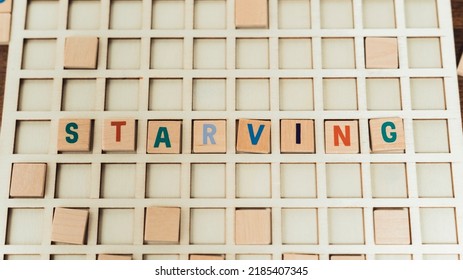 Starving - Society Problems. Colorful Letters On A Square Board Creating The Word - Starving. Wooden Blocks. High Quality Photo