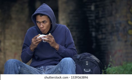 Starving Troubled Teen Chewing Snack Sitting Outdoors, Dangerous City Suburb