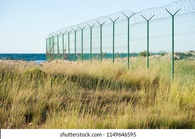 State Border Prison Danger Zone With High Fence With Razor Wire On Empty Sea Coast