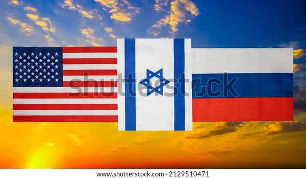 State flags
of the USA, Russia and between them Israel against the background
of a burning sky close-up.
Flags.