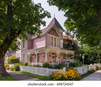 A stately Victorian home with copula is viewed between a pair of ancient maple trees.