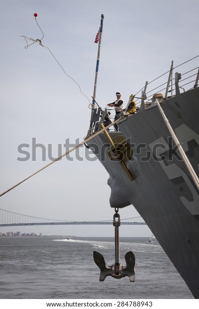STATEN ISLAND, NY - MAY 20 2015: Linesmen work on the\
bow of USS Barry (DDG 52) guided-missile destroyer mooring for\
Fleet Week NY at Sullivans Pier with the Verrazano-Narrows Bridge\
in background. 