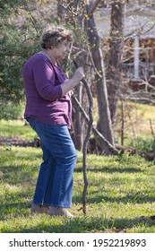 Statesville, NC, USA, April 05 2021. A Little Old Lady With Scoliosis Walking With A Crooked Stile.