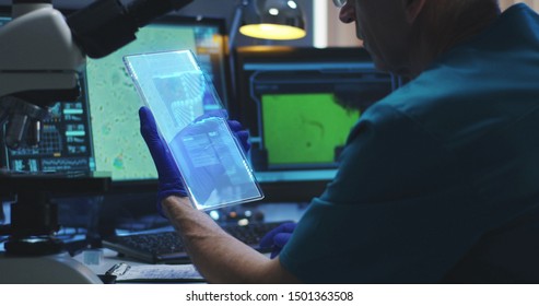 Static shot of a male scientist using a portable holographic display screen for research