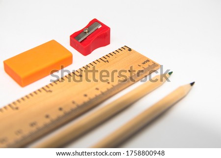 Stationeries Pencil, ruler, eraser and sharpner isolated on white background. Use of selective focus on a particular point on the ruler, with rest of the other items blurred.