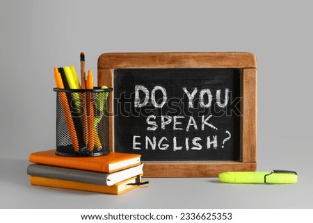 Stationery and blackboard with question DO YOU SPEAK ENGLISH? on grey background