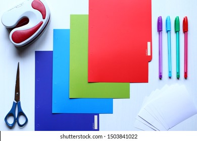 Сomposition of stationery: multi-colored sheets and dividers for notebook, white papers for notes, multi colored pens, scissors and hole puncher