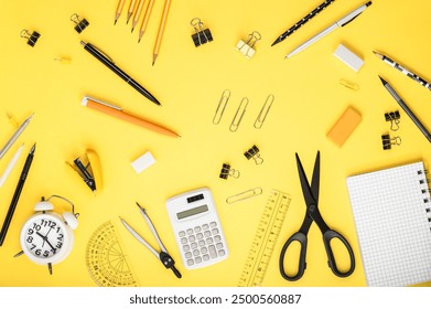 Stationery, notebooks, alarm clock and calculator on a yellow background. Back to school concept. Workspace organization. Copy space. - Powered by Shutterstock