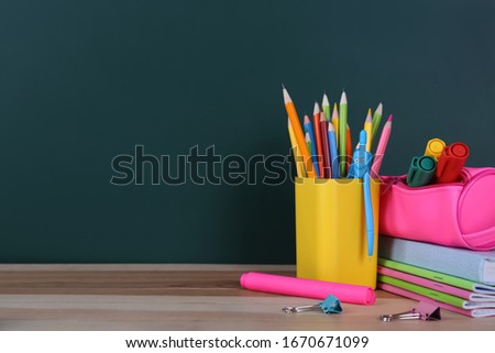 Stationery on wooden table near chalkboard, space for text. Doing homework