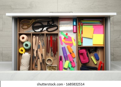 Stationery and sewing accessories in open desk drawer, top view