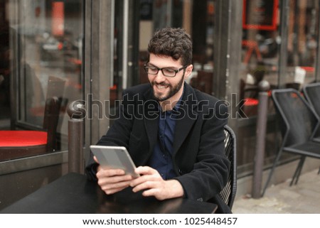 Statistician working with diagram document papers at cafe table outside in  . Hardworking man wears  dark blue shirt. Concept of using modern gadgets and Internet connection for job. 