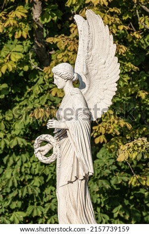 Statue of ancient beautiful winged angel in downtown park of Potsdam in beginning of Autumn at sunset, Germany, portrait, details