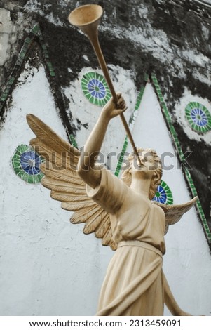 Statue of an angel blowing a trumpet  with church as background