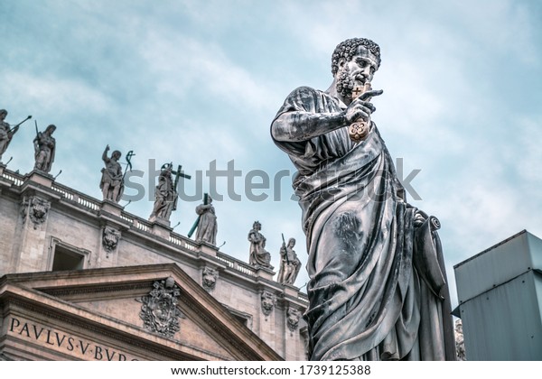Statue of Apostle Peter in front of St Peter\'s\
Basilica, Rome, Italy. Renaissance sculpture of apostle with key on\
dramatic sky background. Roman San Pietro is famous landmark of\
Vatican and Rome.
