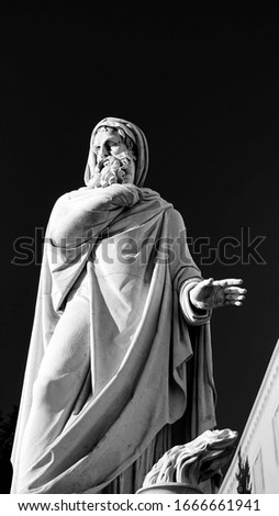 Statue of bearded philosopher man, view from below in the morning sun with blue sky