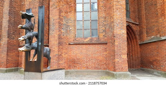 Statue of Bremen Town musicians in Riga, Latvia. Against the background of a red brick wall. Free space for text. Donkey, dog, rooster, cat. - Powered by Shutterstock