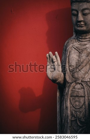 A statue of Buddha in front of a red wall in China.