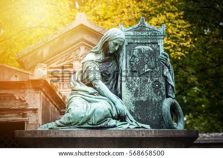 Statue in a cemetery of Paris at sunset