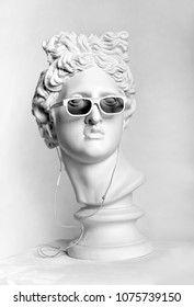 Statue. Earphone. Isolated. Gypsum statue of Apollo's head. Man. Creative. Plaster statue of Apollo's head in earphones and white sunglasses. Head. Black Lives Matter - Shutterstock ID 1075739150