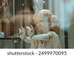 A statue of the god Krishna on a display case behind glass.