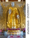 Statue of a Golden robed standing Buddha inside the Sasana Vamsa Sima Shrine Hall for ordination ceremonies at the Dhammikarama Burmese temple,Theravada Buddhist shrine in George Town,Penang,Malaysia