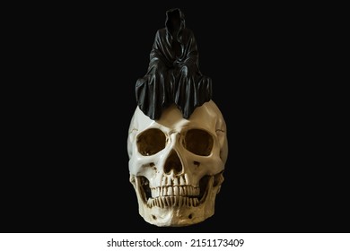 A Statue Of A Grim Reaper Sitting On A Skull.