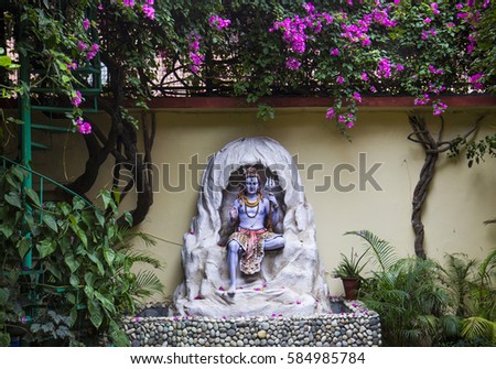 Statue of Hindu Lord Shiva under the beautiful blooming tree, Rishikesh. India