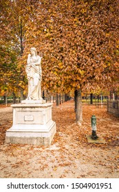 Statue In The Jardin Des Tuileries Covered With Orange Autumn Leaves, Tuileries Garden In Paris France On A Beautiful Fall Day