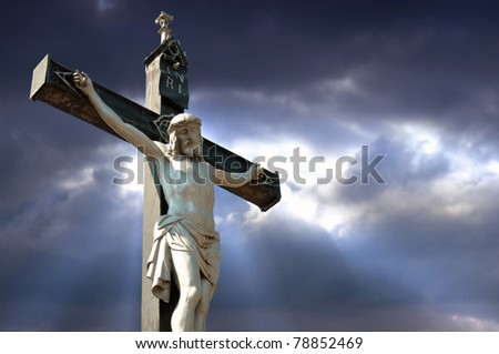 A statue of Jesus Christ crucified against dramatic sky