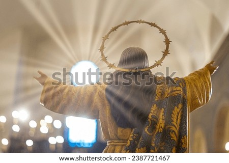 statue of Jesus Christ with open arms, back embracing a ray of light coming from a window