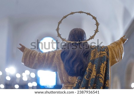 statue of Jesus Christ with open arms, back embracing a ray of light coming from a window