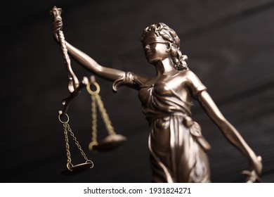 The Statue of Justice - lady justice or justitia the Roman goddess of Justice. Statue on black wooden wall. Concept of judicial trial, courtroom process and lawyers occupation