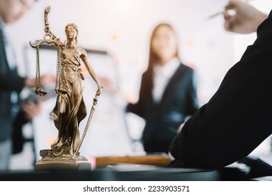 statue of justice with scales and auction hammer, the team meeting at the law firm behind the concept of in office law.