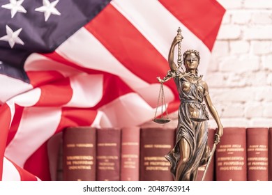 The statue of justice Themis or Iustitia, the blindfolded goddess of justice against a flag of the United States of America, as a legal concept.