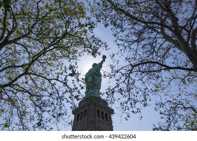 Statue of Liberty seen between tree branches on Liberty Island